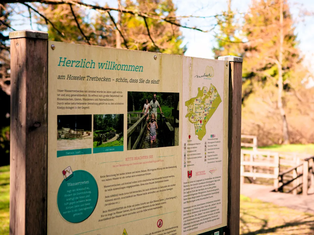 Infotafel „Herzlich willkommen am Hoxeler Tretbecken“ mit Karte und Hinweisen, im Hintergrund die Anlage